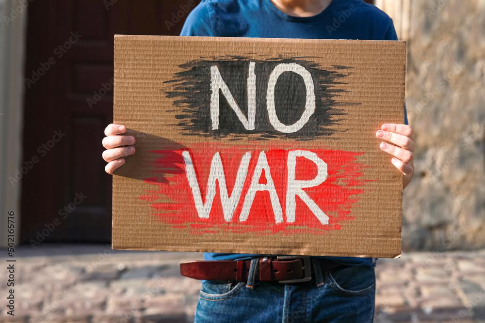 Poster man holding poster with words no war on city street, closeup