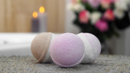 Colorful bath bombs on wicker mat in bathroom, closeup