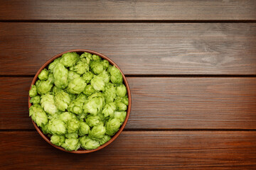 Bowl with fresh green hops on wooden table, top view. Space for text