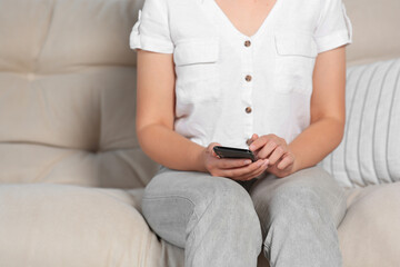 Woman using smartphone on sofa at home, closeup