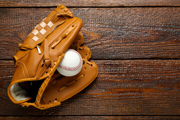 Leather baseball glove with ball on wooden table, top view. Space for text