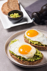 Avocado egg sandwich with a glass of water. Healthy light breakfast concept. Whole grain toasts with mashed avocado and fried eggs