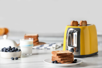 Fototapeta na wymiar Yellow toaster with roasted bread slices, blueberries and glass of milk on white marble table