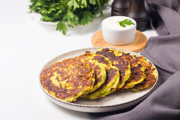 Vegetarian zucchini fritters or courgettes pancakes, served with fresh herbs and sour cream.