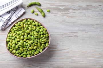 Organic edamame beans on light wooden table, flat lay. Space for text