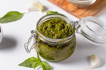 Basil pesto sauce in a jar. Ingredients for cooking, cheese, parmesan, garlic, olive oil. 