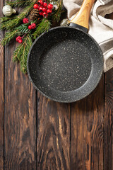 Empty cooking frying pan with tablecloth, Christmas tree and decor on wooden background. Flat mock up for design. View from above. Copy space.