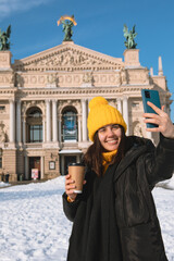 Fototapeta na wymiar woman traveler drinking coffee to go taking selfie in front of opera building