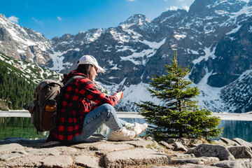 A woman is sitting on the shore of a lake. Morskie Oko, Tatras mountains. © phpetrunina14
