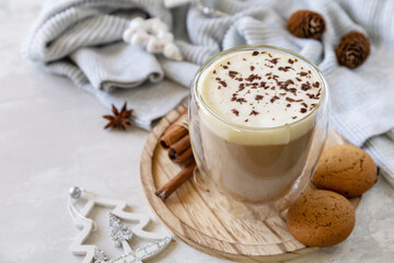 Seasonal winter concept with hot drink. Latte spice coffee, warm pullover and Christmas decor on gray background. Copy space.