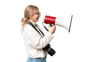 Young photographer English woman over isolated background shouting through a megaphone