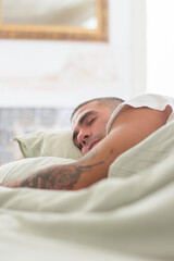 Obraz na płótnie Canvas Peaceful man sleeping on pillow in bed in morning. Vertical shot of handsome Caucasian man having rest after working day, lying in bed under blanket. Sleep cycle, dream concept