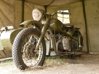 A military motorcycle with a sidecar under an awning. Military camouflage motor vehicles of the Second World War.