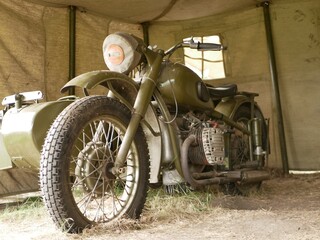 A military motorcycle with a sidecar under an awning. Military camouflage motor vehicles of the Second World War.
