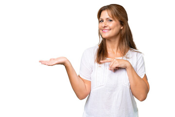 Middle-aged caucasian woman over isolated background holding copyspace imaginary on the palm to insert an ad