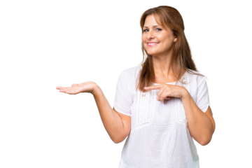 Middle-aged caucasian woman over isolated background holding copyspace imaginary on the palm to insert an ad