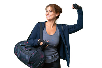 Middle-aged sport woman with sport bag over isolated background doing strong gesture