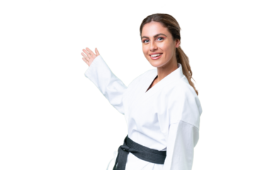 Young Uruguayan woman doing karate over isolated background extending hands to the side for inviting to come