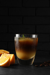 Tasty refreshing drink with coffee and orange juice on grey table against dark background