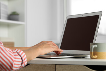 Young woman working with laptop at workplace in office, closeup