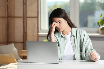 Young woman suffering from eyestrain at desk in office