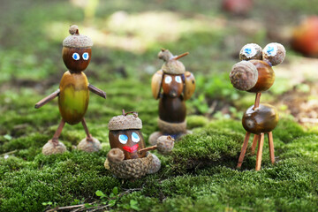 Cute figures made of acorns on green moss outdoors