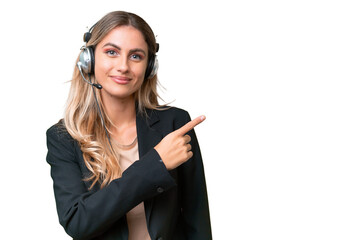 Telemarketer pretty Uruguayan woman working with a headset over isolated background pointing to the side to present a product