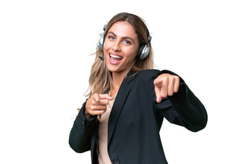 Telemarketer pretty Uruguayan woman working with a headset over isolated background pointing to the...