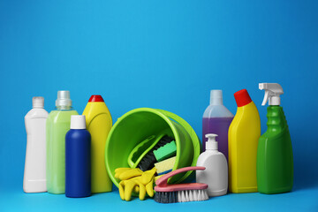 Green bucket, cleaning supplies and tools on light blue background