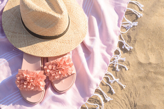 Blanket With Stylish Slippers And Straw Hat On Sandy Beach, Above View. Space For Text