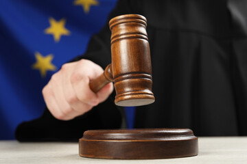 Judge with gavel at wooden table against flag of European Union, closeup - obrazy, fototapety, plakaty