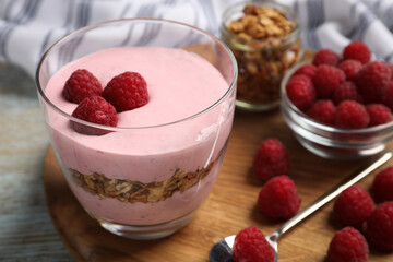 Tray with delicious yogurt, raspberries and granola on old wooden table, closeup