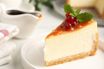 Piece of delicious caramel cheesecake with red currants and mint served on white table, closeup