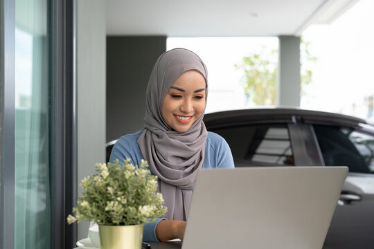 Portrait Of Muslim Asian Woman In Hijab Using Laptop At Home.