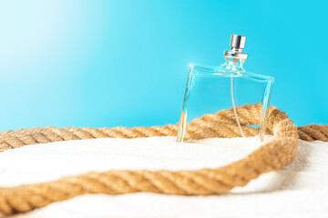 Perfumery, summer fragrance concept with transparent perfume bottle lying on a sandy beach near the...