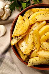 Bowl with tasty baked potato wedges and spices on table, top view