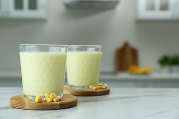 Tasty fresh corn milk in glasses on white table indoors. Space for text
