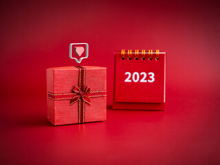 3d love like heart icons floating on small red present gift box with 2023 year of desk calendar on...