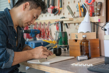DIY concept, close up. Woodworking and crafts tools. Handicraft Carpentry. Male designers' hands work in their workshops, making a draw of custom furniture.