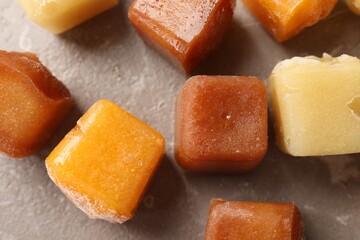 Different frozen fruit puree cubes on brown marble table, flat lay