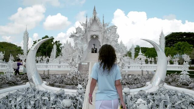 A girl tourist walks across the bridge over the underworld. A popular tourist spot in northern Thailand known as the White Temple.
