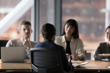 Applicant being interviewed by group of corporate HR managers, seated at table in boardroom in...