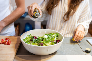 Female hand pouring balsamic vinegar on the fresh vegetables salad