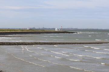 a seascape at the dutch coast in Terneuzen with little waves in the westerschelde sea between the breakwaters with upcoming tide