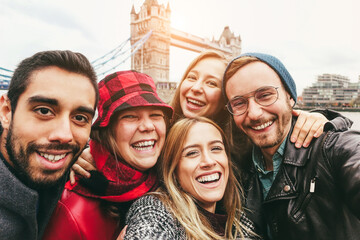 Happy friends having fun taking selfie with mobile phone in London with Tower Bridge in background...