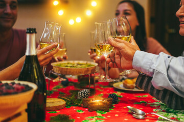 Happy family cheering with wine while eating Christmas holiday dinner together - Focus on right glass