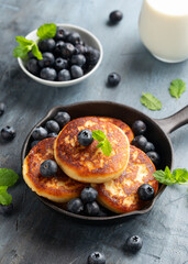 Cottage cheese pancakes served in cast iron frying pan with blueberries and mint leaves. Healthy breakfast food.