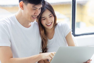 Close up Young Asian couple using laptop computer together at home with enjoying life Happy girlfriend and boyfriend or wife and husband use loptop computer on weekend holiday with happiness