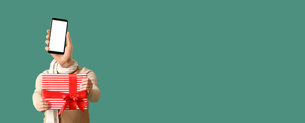 Fototapeta premium Man with modern mobile phone and hand instead of his head and Christmas gift on green background with space for text
