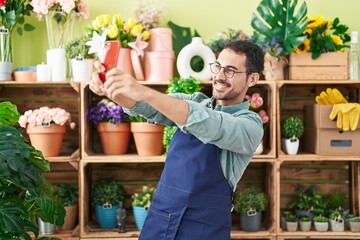 Young hispanic man florist make selfie by smartphone at flower shop